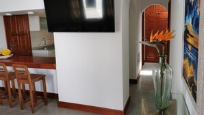 Una cuina moderna amb televisió de pantalla plana, cadires de fusta, taula de menjador i un ram de flors.