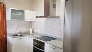 Una cuina moderna amb armaris blancs, un refrigerador d'acer inoxidable, forn de sobre i microones.