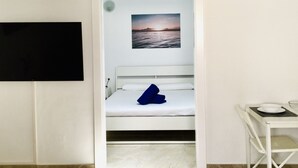 A small, compact room with a bed, a TV mounted on the wall, and a small table with a bowl and plate. - One bedroom apartment with shared terrace (TAHICHE)