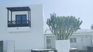 A modern building with a balcony, a large cactus, and a stone wall. - One bedroom apartment with shared terrace (TAHICHE)