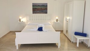 A neatly arranged bedroom with a bed, bedside lamps, a painting, a wardrobe, and a bench. - One bedroom apartment with balcony (TAHICHE)