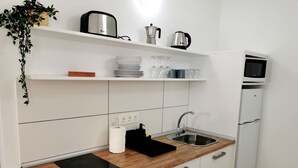 A compact kitchen with a built-in microwave, a sink, and a wooden countertop. - One bedroom apartment with balcony (TAHICHE)