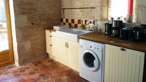 A compact kitchen with a washing machine, a sink, and a wooden countertop. - Le Petit Cloucq (Damvix)