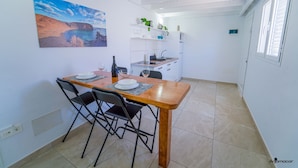 A compact kitchen with a dining area, white walls, and a large window. - One bedroom double apartment whit terrace (TAHICHE)