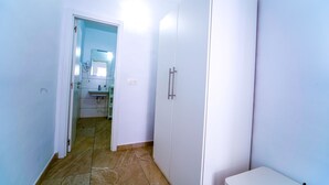 A narrow hallway with a bathroom containing a sink, mirror, and a white cabinet.