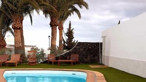 Uma piscina com espreguiçadeiras e palmeiras.