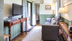Un salon confortable avec une télévision, un canapé, une petite table en bois sur laquelle sont posés des livres et une lampe.