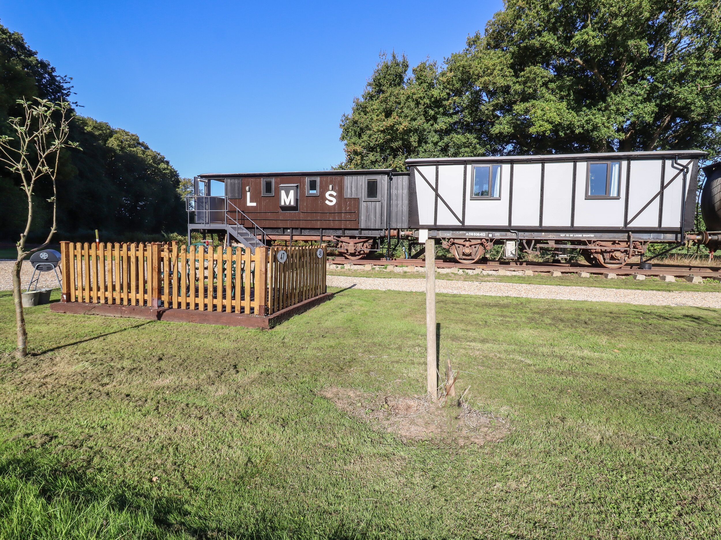 A train car with 'LMS' on the side, a wooden fence, and a grassy area.