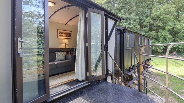 Un wagon de train moderne doté d’une porte coulissante, d’un canapé, d’une lampe et d’un tableau accroché au mur.