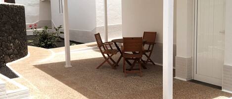 Un patio couvert avec une table et des chaises, des murs blancs et une porte.
