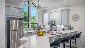 Una cocina moderna con una isla grande, electrodomésticos de acero inoxidable y vistas a zonas verdes.