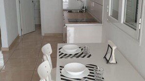 Una cocina moderna con un lavaplatos integrado y un comedor con una mesa dispuesta para dos.