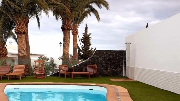 Una piscina con una pared de piedra y palmeras al fondo.