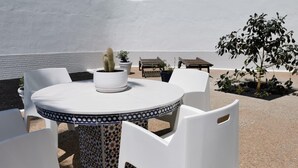 Une table ronde, des chaises blanches et une plante en pot.