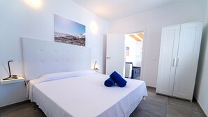Une chambre à coucher avec un grand lit, une table de chevet, une armoire et une porte donnant sur une autre pièce.