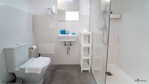 Un bagno moderno con WC, lavandino, specchio e doccia.