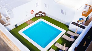 Ein Pool auf dem Dach mit blauem Wasser, umgeben von Liegestühlen und einer kleinen Sitzecke.