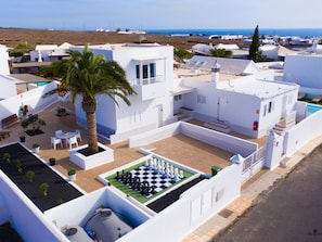 A residential area with white buildings, a palm tree, and a chessboard in the courtyard. - One bedroom apartment with balcony (TAHICHE)