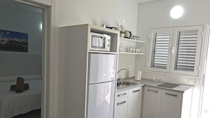 Una cocina moderna con armarios blancos, horno empotrado y ventana con persianas.