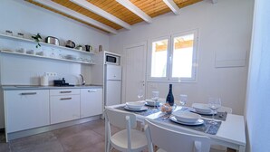A modern kitchen with white cabinets, a dining table set for four, and a window providing natural light. - Apartment two bedrooms with balcony (TAHICHE)