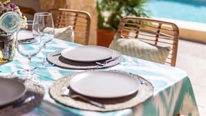 Tavolo imbandito con piatti, bicchieri e posate, con vista su una piscina.