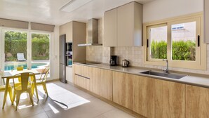 Una cucina moderna con forno integrato, macchina da caffè e finestra con vista su un giardino.