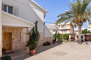 A courtyard with a palm tree, potted plants, a wooden door, and a stone wall. - Vacation Home 'Villa Santa Lucia' with Private Pool, Terraces and Wi-Fi (Calvia)