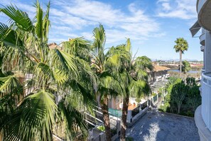 Un patio con palmeras, un sendero de piedra y vistas a edificios y una masa de agua.