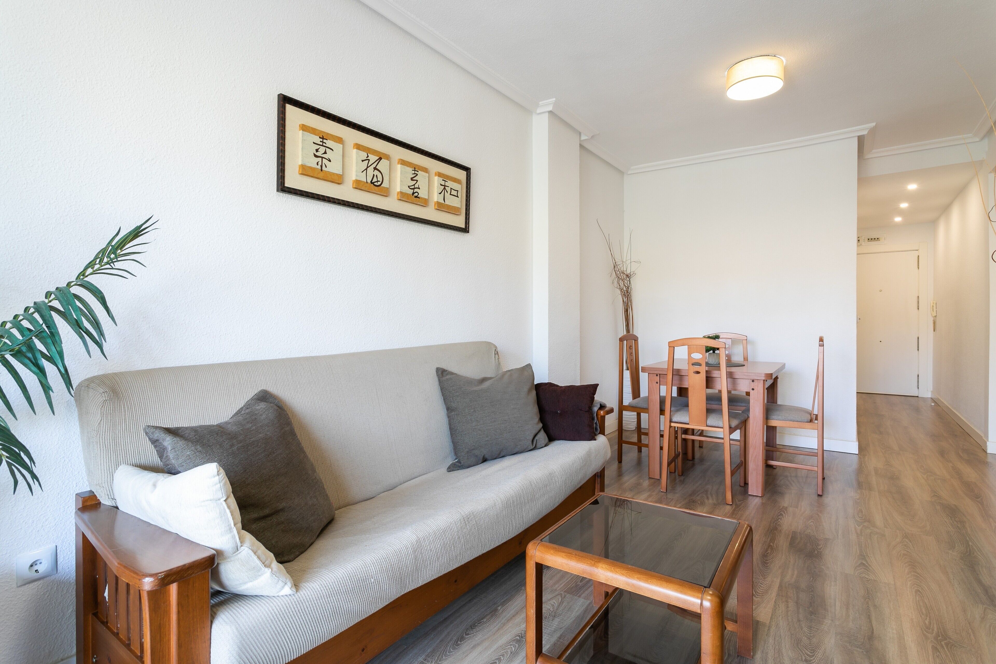 A living room with a sofa, a coffee table, and a dining area with chairs and a table.