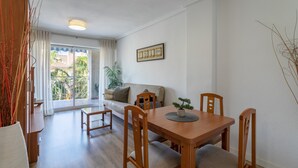 Un coin repas avec une table et des chaises en bois, un canapé, une plante en pot et une fenêtre avec des rideaux.