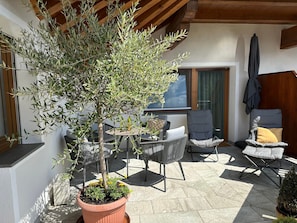 Un espace extérieur aménagé avec des sièges, un arbre en pot, des chaises et une table.
