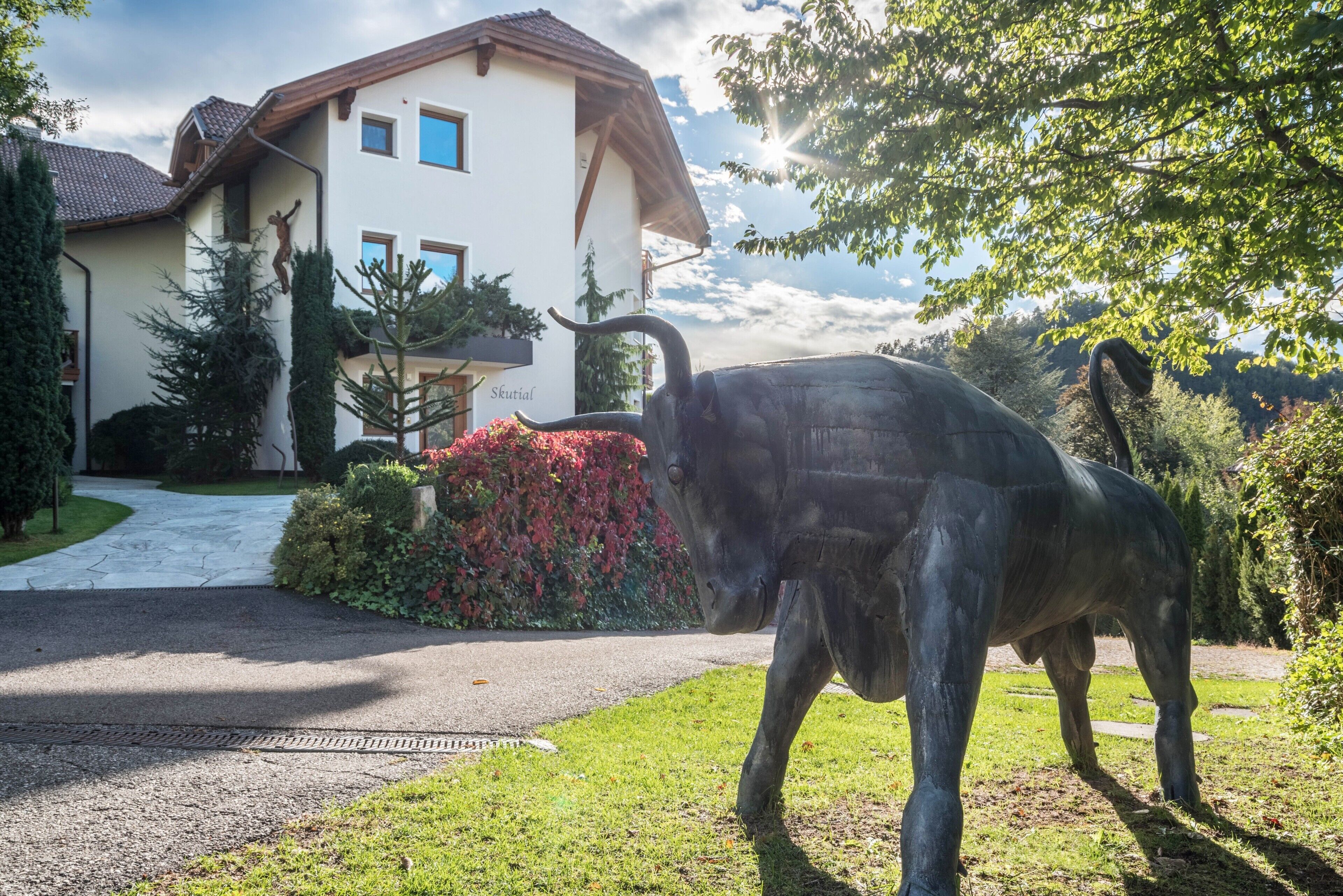 Eine Bullenstatue vor einem Haus mit Auffahrt und gepflegtem Garten.