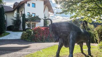 Eine Bullenstatue vor einem Haus mit Auffahrt und gepflegtem Garten.