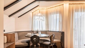 A corner seating area with a round table, chairs, and a pendant light. - Apartment 'Residence Skutial - Schlern' with Mountain View, Balconies & Wi-Fi (Castelrotto)