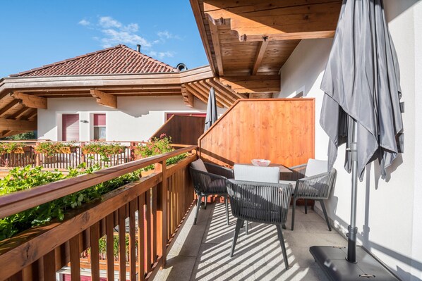 A balcony with wooden railings, a table with chairs, and a wooden partition.