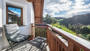A balcony with a wooden railing, a chair, and a potted plant. - Apartment 'Residence Skutial - Schlern' with Mountain View, Balconies & Wi-Fi (Castelrotto)
