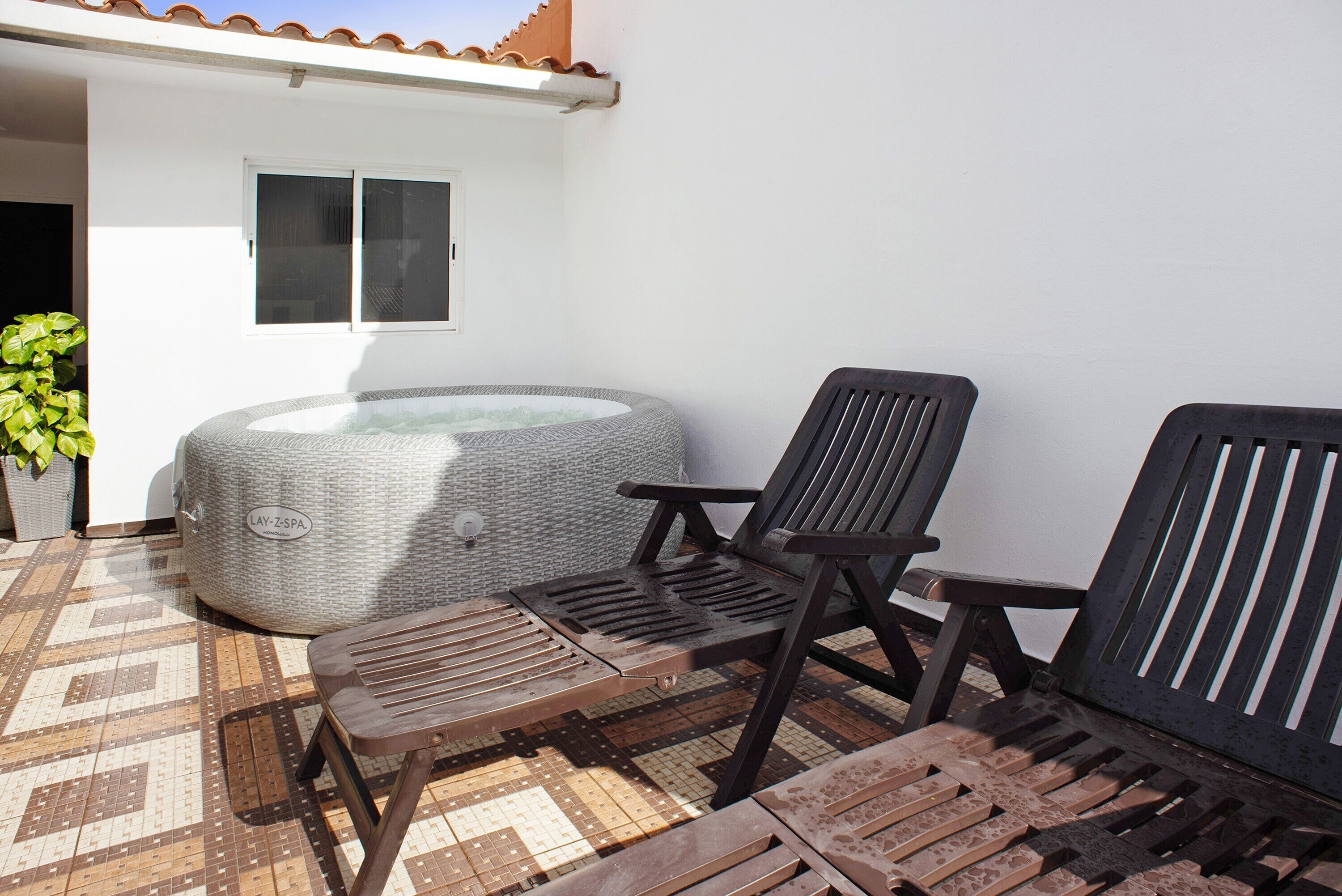 Een wellnessruimte met een jacuzzi, twee houten stoelen en een vloer met een patroon.