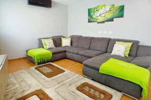 A living room with a sectional sofa, a bright green throw blanket, and a patterned rug. - Vacation Home 'Atico Las Vegas' with Sea View, Whirlpool and Wi-Fi (Las Vegas)