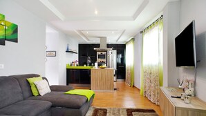 Una sala de estar moderna con un sofá gris, una mesa de centro de madera y un televisor a la derecha.