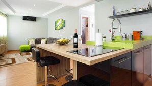 Una cocina moderna con una isla de madera, taburetes de bar, una botella de vino y un lavabo.