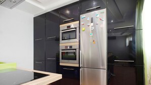 Una cocina moderna con gabinetes negros, un refrigerador de acero inoxidable y un horno empotrado.