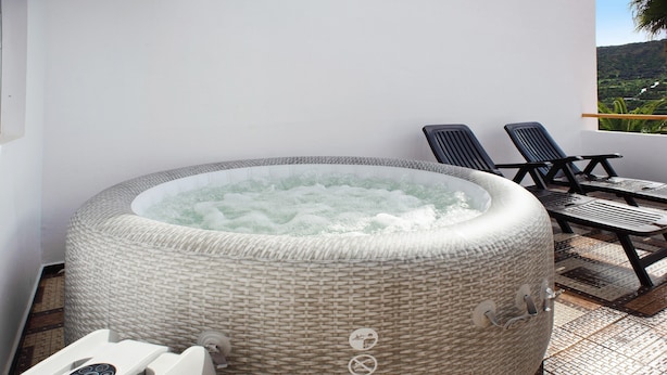 Un jacuzzi con panel de control, dos sillones de descanso y vista a un paisaje.
