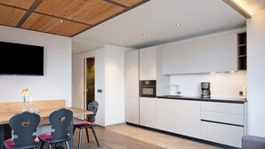 Una cucina moderna con mobili bianchi, soffitto in legno e zona pranzo con tavolo e sedie.