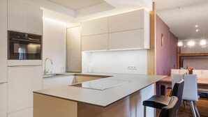 Une cuisine moderne dotée d’un îlot central, d’appareils électroménagers intégrés et d’un coin repas avec une table et des chaises.