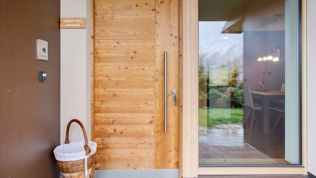 Une porte en bois avec une enseigne, un panier et une porte vitrée donnant sur un espace extérieur.