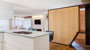 Une cuisine moderne avec des meubles blancs, un îlot central et un mur d’accent en bois.