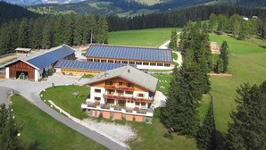 A building with solar panels, a large lawn, and a mountainous backdrop. - Apartment "Angerle Alm Apt Similde A" with Private Terrace, Shared Garden & Wi-Fi (carezza Nova Levante)