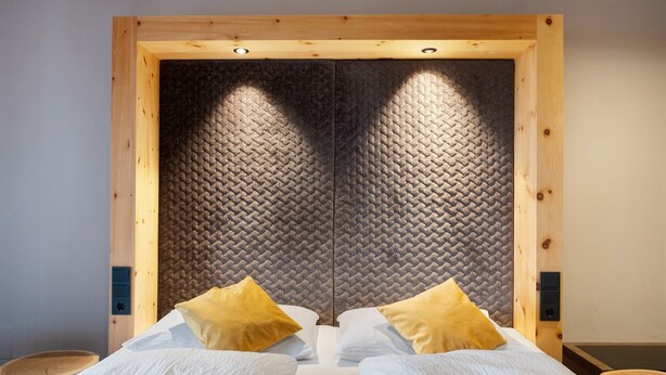 A room with a bed, two pillows, a wooden headboard, and a small wooden stool. - Apartment "Angerle Alm Apt Similde A" with Private Terrace, Shared Garden & Wi-Fi (carezza Nova Levante)