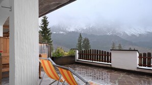 A patio with chairs, a stone floor, a wooden fence, and a view of snow-capped mountains. - Apartment "Angerle Alm Apt Similde A" with Private Terrace, Shared Garden & Wi-Fi (carezza Nova Levante)