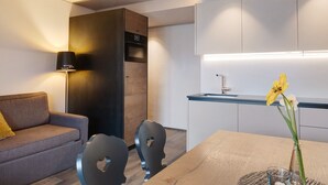 A modern kitchen with a built-in oven, a dining table with chairs, and a vase with flowers on the table. - Apartment "Angerle Alm Apt Similde A" with Private Terrace, Shared Garden & Wi-Fi (carezza Nova Levante)